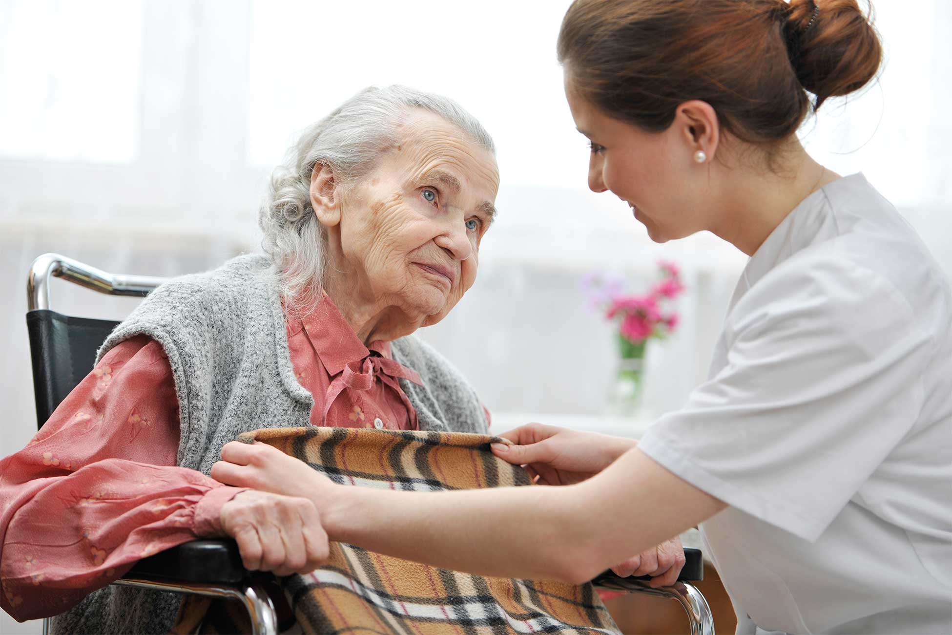 Nurse providing blanket to patient in wheelchair
